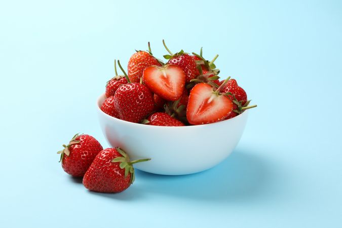 Bowl with tasty strawberry on blue background. Summer berry
