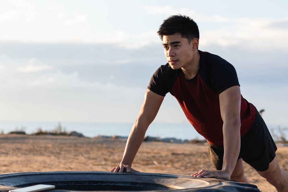 Athletic man doing push ups against tire