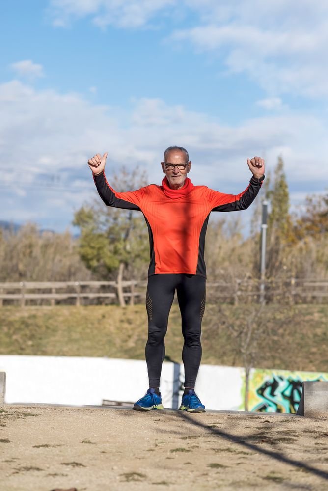 Fit older man with arms up in victory after run