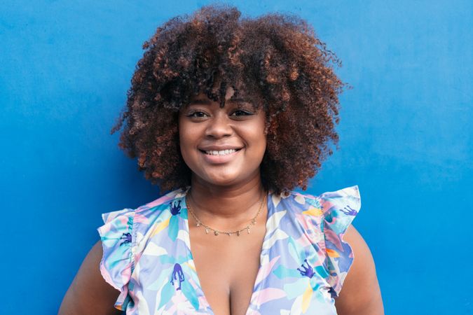 Black smiling woman with blue background.