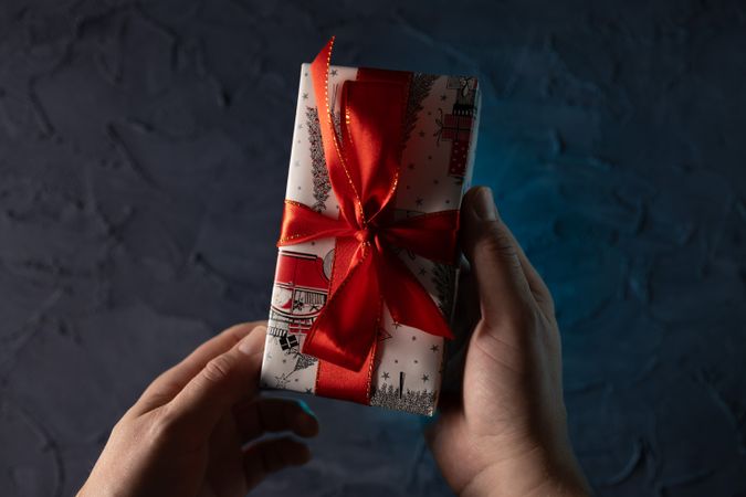 Man holding Christmas gift near tree