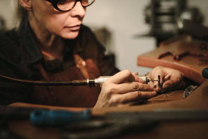 Female jewelry maker polishing a product at her workbench