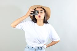 Asian Female Traveler Wearing Summer Hat and Holding Paper Camera While Traveling