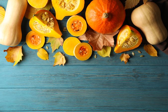 Composition with pumpkin, squash, seeds and leaves on wooden background