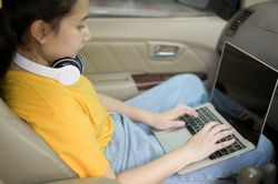 Young woman working with laptop while traveling in the car.