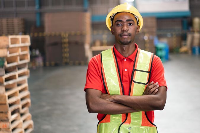 Man in PPE gear standing in distribution center with arms crossed