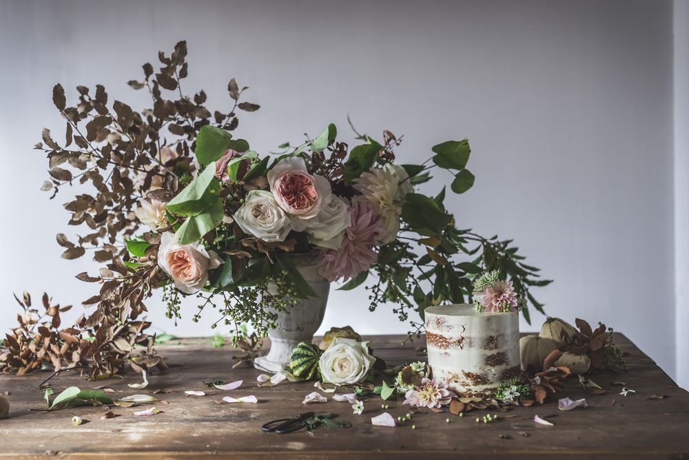 plate with cake decorated flower on table with bouquet of blooms in vase