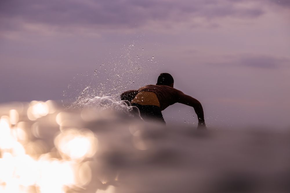 Man on surf board floating on water and cloudy sky