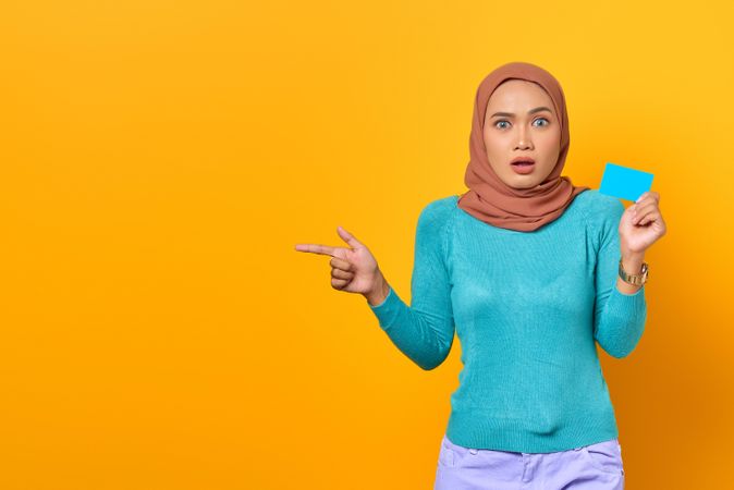 Muslim woman looking surprised with credit card