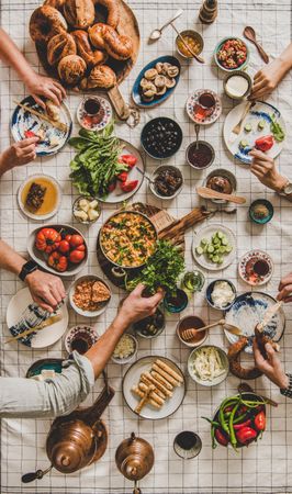 Group of people at Turkish style fresh breakfast with eggs, breads, vegetables, vertical composition