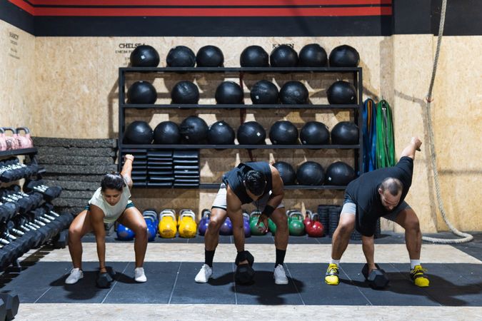 Hispanic sportspeople lifting kettlebells during powerlifting training
