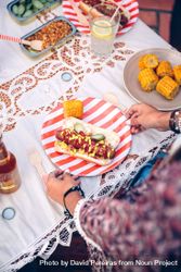 Woman holding plate with hot dog and corn 5lVVMo