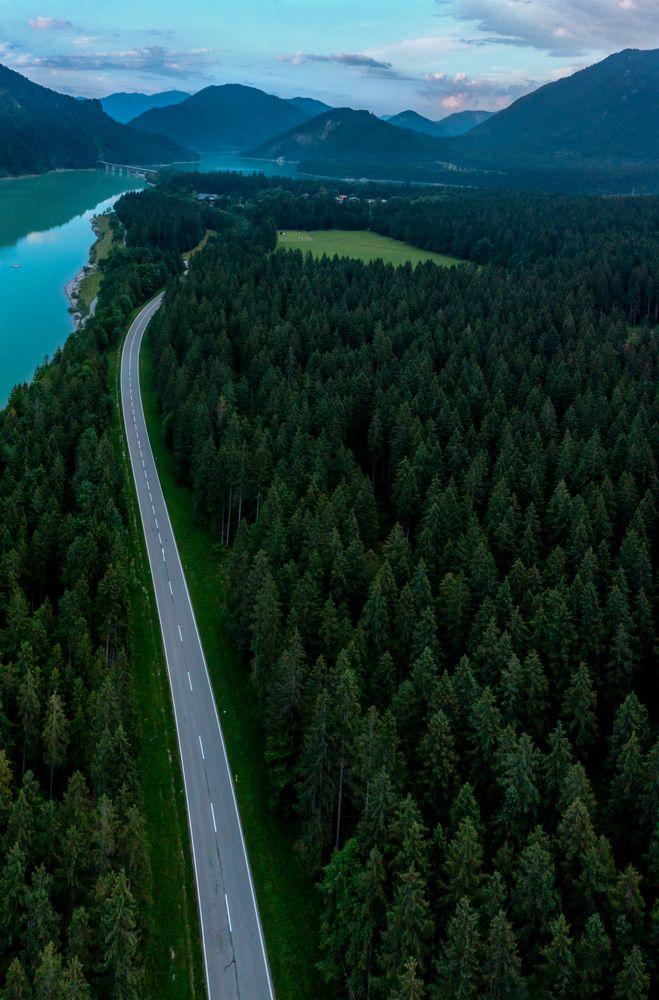 Drone aerial view with forest road on Sylvenstein lakeshore in Bavaria, Germany