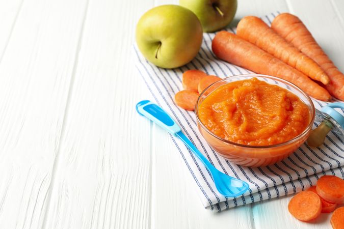 Composition with carrot puree on plain wooden background. Baby food