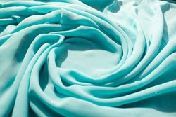Spiral Twisted Turquoise wavy crumpled fabric with little sparkling dust and copy space in center, texture and  background.