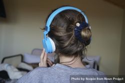 Back view of young woman listening to audio using headphone 5zKzQ4