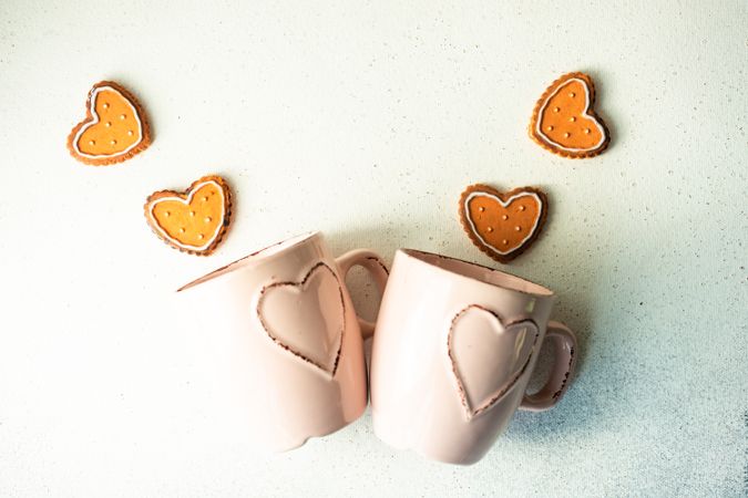 St. Valentine's day card concept with two pink mugs laying on counter with heart cookies