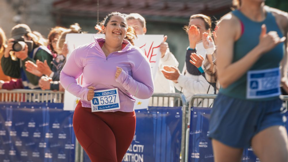 Portrait of a Smiling  Female Runner Crossing the Finish Line and Demonstrating her Willpower.