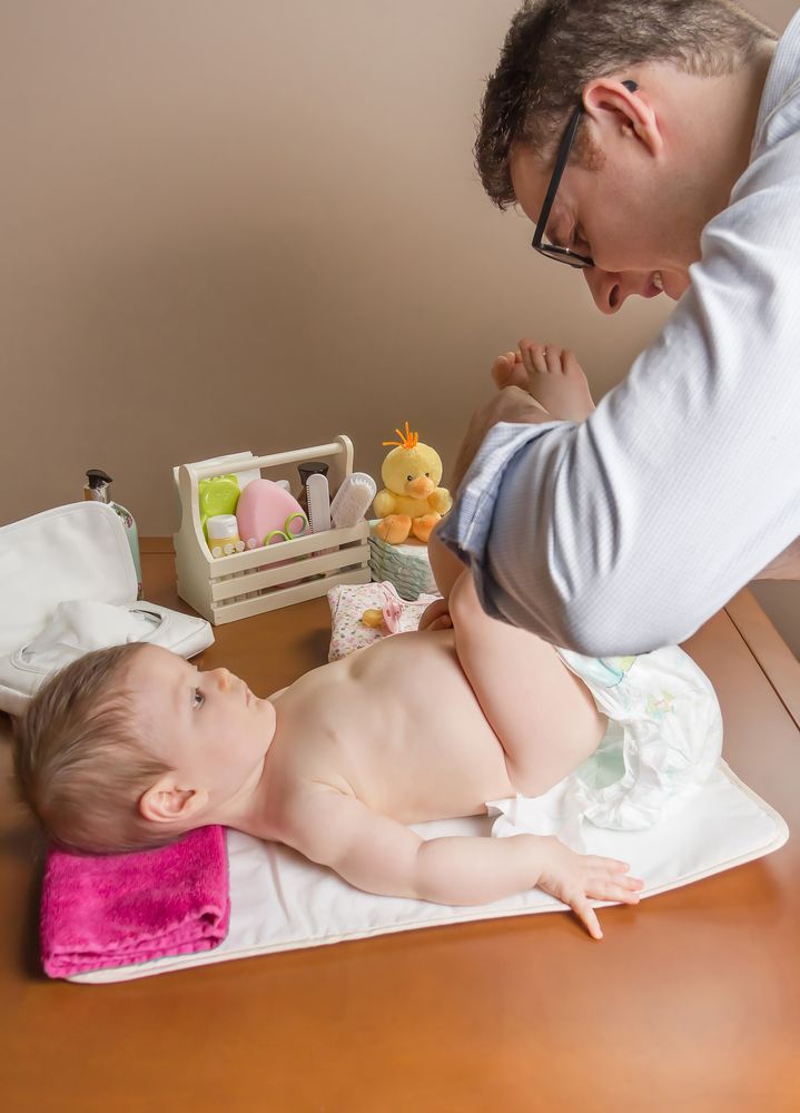 Father changing diaper of cute baby
