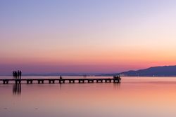 Anonymous tourists on pier during sundown
