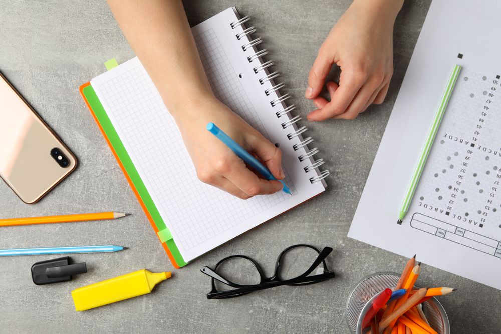 Top view of person’s hand writing in a notebook on desk