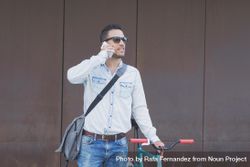 Male in sunglasses standing with red and green bicycle and looking around speaking on phone 4OmQa0