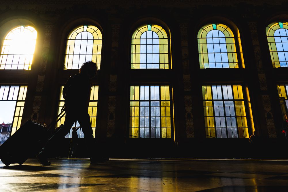 Silhouette of man dragging suitcase at a station