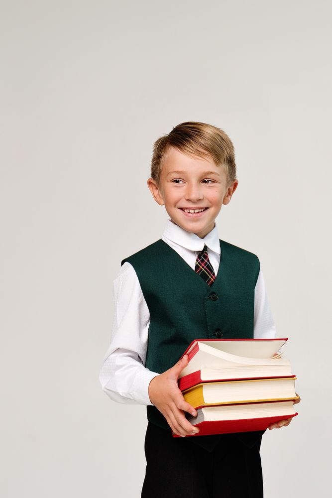 Portrait handsome preteen schoolboy in uniform in front of plain background