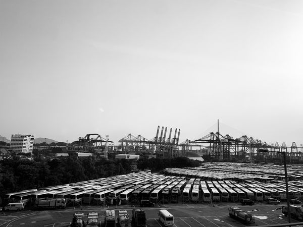 Grayscale photo of busses parked in parking lot near seaport in Hong Kong