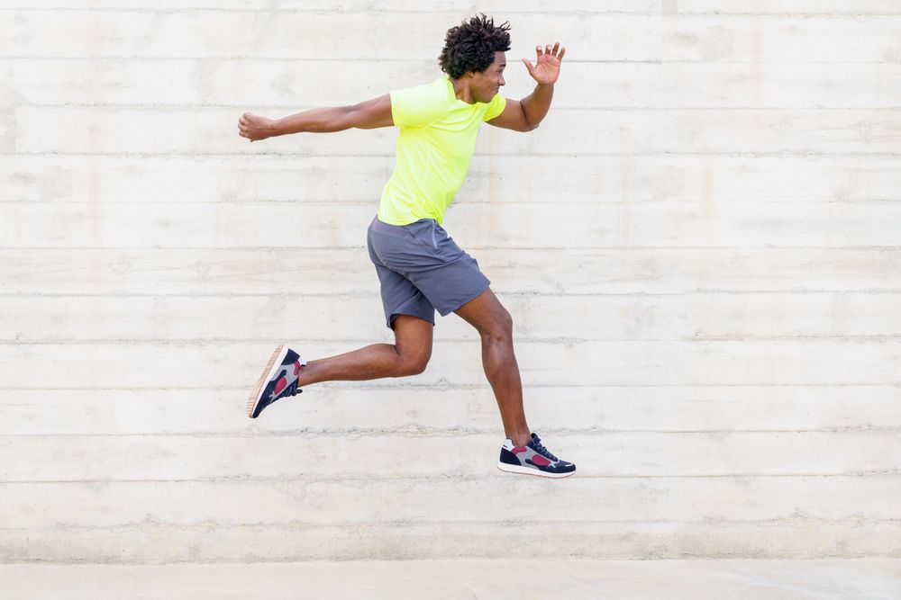 Side view of man jumping in neon shirt