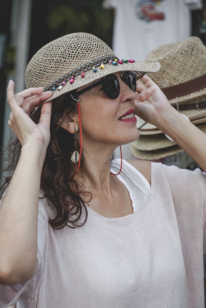 Woman choosing summer hat on street market