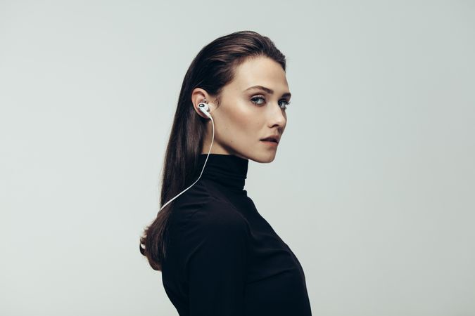 Portrait of beautiful woman in top wearing earphones staring at camera