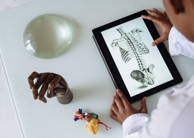 Top view of a boy holding a tablet with photo of human skeleton