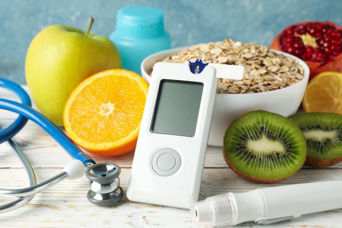 Blood glucose meter and diabetic food on wooden table