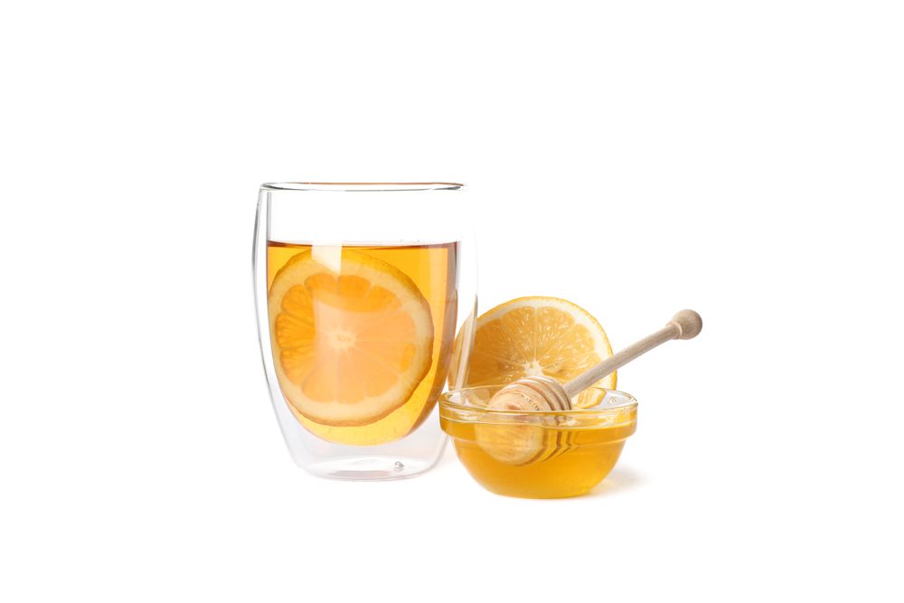 Glass of tea with lemon, honey and dipper isolated on blank background