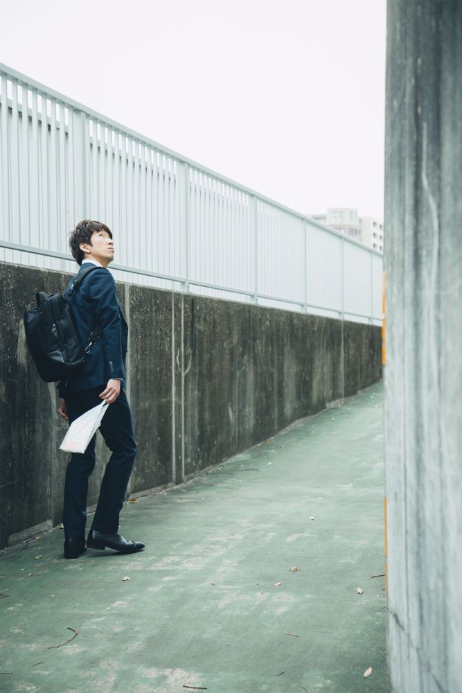 Man in dark in dark suit standing on sidewalk