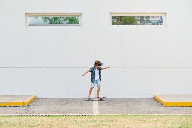 Anonymous boy in VR headset skateboarding on street