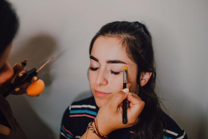Young woman getting makeup by makeup artist in salon