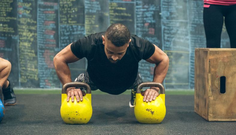 Sportsman doing push-ups with kettlebells