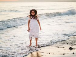 Excited girl running along beach in daylight