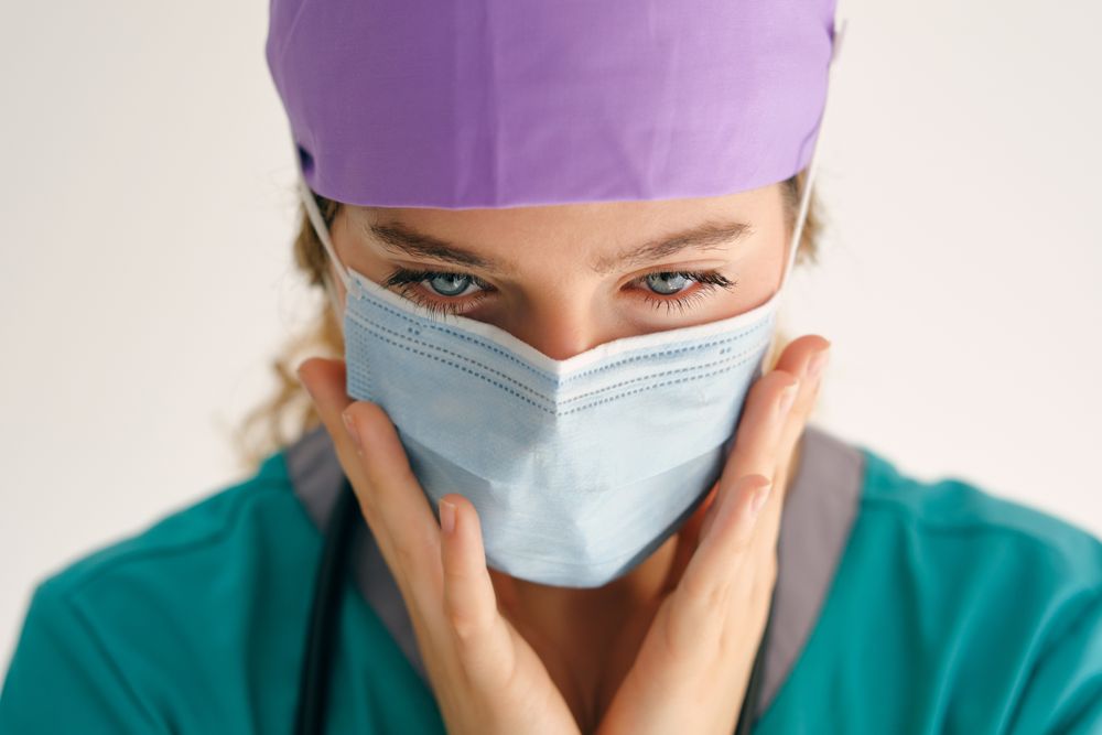 Woman in mask touching face and looking down