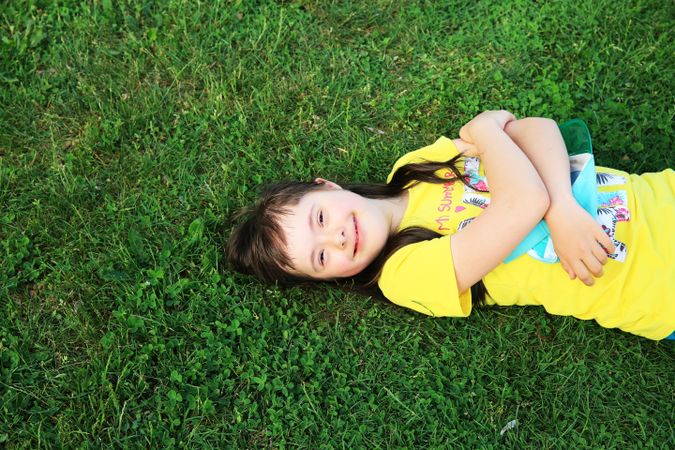 Girl with Down syndrome lying on the grass and smiling