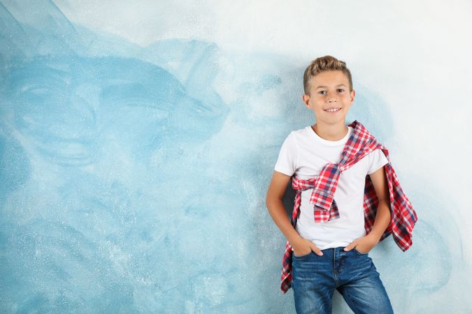 Boy in t-shirt, jeans and shirt against color background, space for text