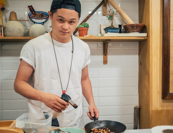 Asian male cooking in kitchen