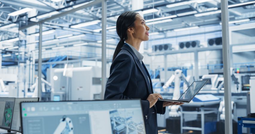 Close Up Of Electronics Manufacturing Technician Working on a Laptop Computer at a Factory Space. Asian Female Specialist Developing, Maintaining, and Fine-Tuning Programs for Production and Assembly.