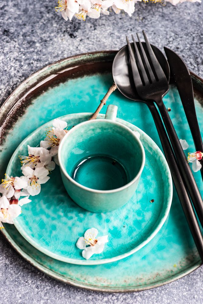 Spring floral concept with top view of apricot blossom branch on teal plates