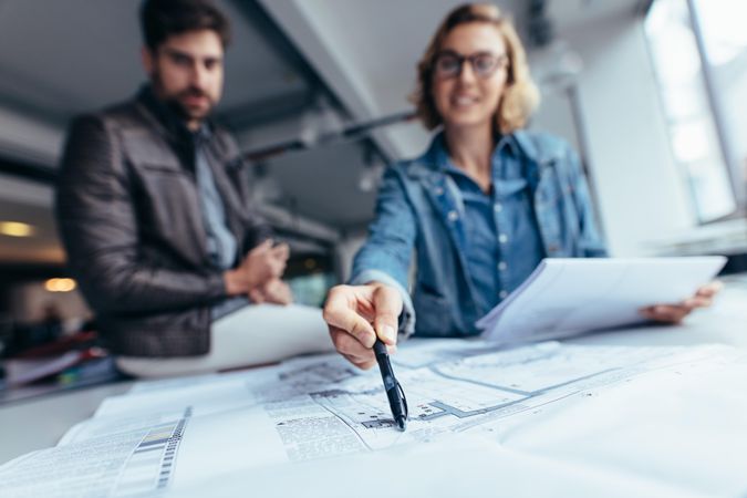 Designers working on blueprint on table in office
