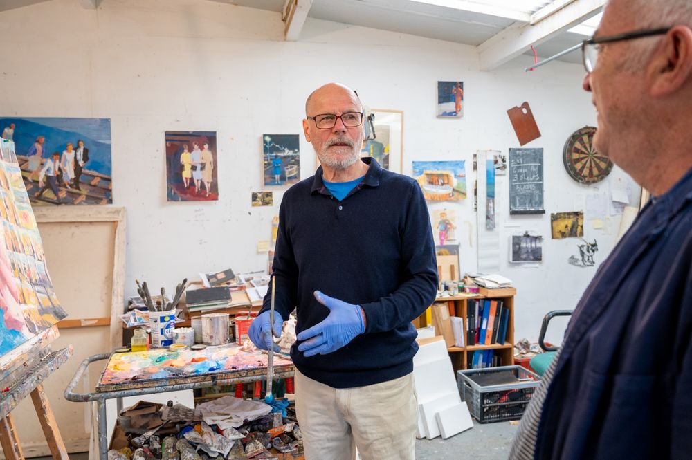 Older male artist talking with male friend in studio