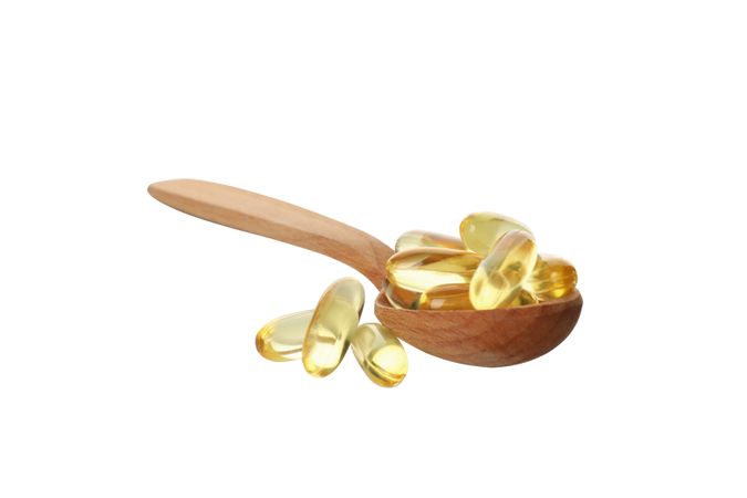 Wooden spoon with omega pills, isolated on blank background