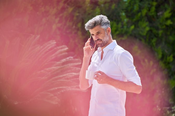 Grey haired man speaking on smartphone outside